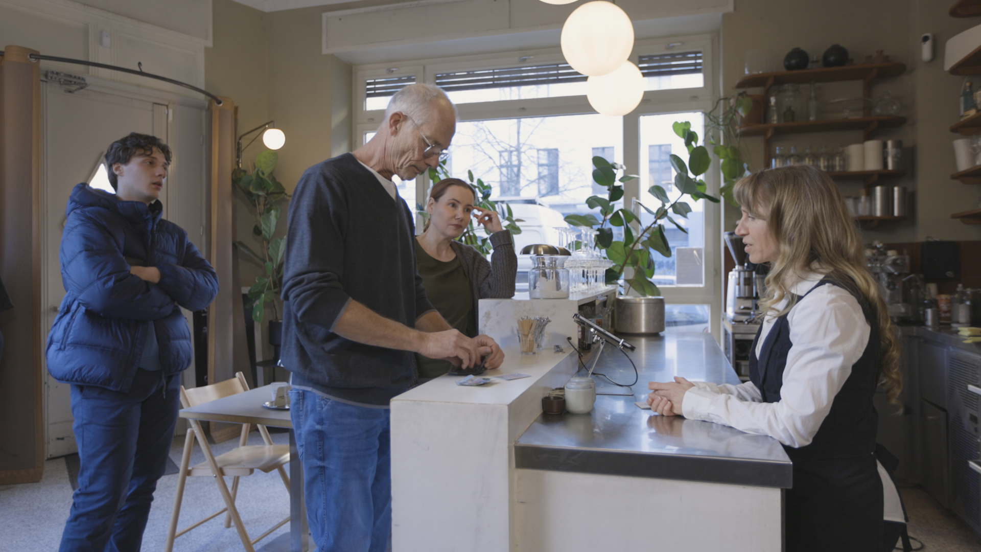  Filmszene zeigt demenzerkrankten Mann beim bezahlen in einem Café